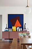 Modern graphic painting above mauve sideboard in dining room