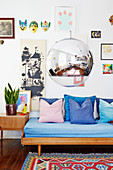 Low-hanging spherical lamp in front of couch below gallery of pictures