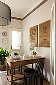 Pictures made from hessian sacks above old wooden table and stacked chairs