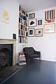 Armchair in corner below bookcase and gallery of pictures on wall