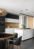Black upholstered chairs at round table in front of open-plan kitchen