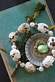Circlet of threaded quail eggs around turquoise egg