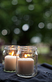 Two lit pillar candles in screw-top jars