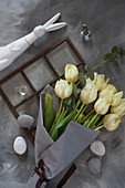 Bunch of white tulips in grey paper and Easter eggs