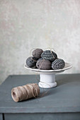 Easter eggs wrapped in fabric on cake stand and reel of twine