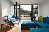 Blaue Polstermöbel im Wohnzimmer mit offener Terrassentür