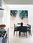 Black dining set in front of large artwork in open-plan kitchen
