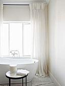 Free-standing bathtub in front of window in white bathroom