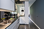 Brightly lit kitchen with grey walls and serving hatch