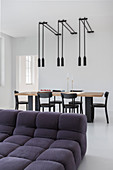View across sofa to dining table, black chairs and pendant lamps