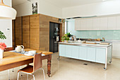 Wooden table in front of a modern open kitchen and wall with wooden paneling