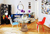 Metal table with round glass top, various chairs, screen and blue couch in living room