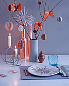 Christmas place setting, ornaments, candles and modern baubles hung from branches on table