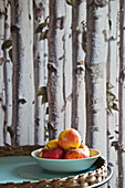 Fresh apples in bowl in front of wallpaper with pattern of bitch trunks
