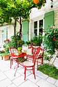 Red garden furniture in seating area outside French stone house