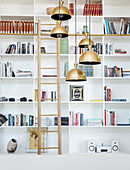 Library ladder and pendant lamps in front of white shelves