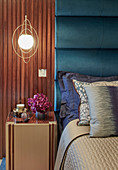 Pendant lamps in golden rings above bedside cabinet next to bed