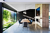 Middle wall with built-in fireplace, in front of it a long dining table with chairs and glass front