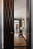 View through open double door with brass insert on chair with high back in elegant hallway