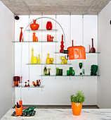 Murano glassware on glass shelves and arc lamp with orange shade