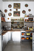 Kitchen counters, cement-tiled splashback and collection of decorative plates on wall above