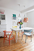 Various colourful chair at white dining table on wooden floor