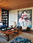 Rustikaler Holztisch und Sitzbank vor großformatigem Bild an Natursteinwand im Wohnzimmer