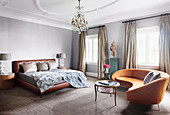 Half-round, cognac-colored sofa in the bedroom with a leather bed