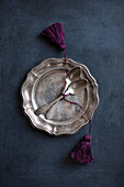 Vintage cutlery with hand-made tassels on pewter plate