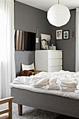 Blick ins Schlafzimmer mit weißer Kommode und grauen Wänden