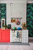 Old kitchen stove against tiled wall flanked by jungle-patterned wallpaper