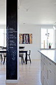 Column painted with chalkboard paint in front of dining table and black chairs