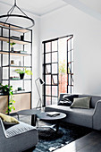 Gray upholstered furniture, black side tables and an open shelf in the living room