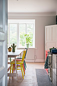 View into kitchen with colourful chairs around table in front of large window