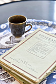 Old magazines and brown mug on blue-patterned tray