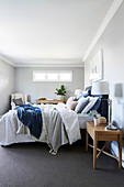 Double bed with pillows and blue bed headboard in the bedroom with light gray walls