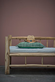 Cowboy hat and cushions on rustic wooden bench against dusky-pink wall