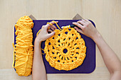 Hands crocheting with yellow jersey yarn