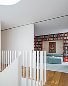 Blick vom Treppenabsatz ins Schlafzimmer mit Bücherregal um das Bett