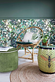Ceramic stool and wicker chair in front of jungle-patterned wallpaper