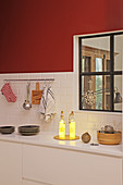 Leuchtende Flaschen in der Küche mit roter Wand und Innenfenster