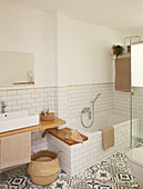 Bathtub, patterned floor and walls tiled to half height in bathroom
