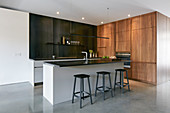 Cubic wooden module and island counter in fitted kitchen without wall units
