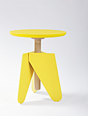 Bright yellow, three-legged stool with threaded rod used as side table