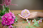 Hand hält Blumenkugel aus Chrysanthemen und Erika