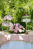 Romantic table in the garden with flower arrangements and cake stand