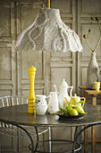 Crockery on table below lamp with knitted lampshade