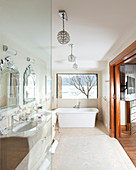 Twin sinks and free-standing bathtub in bathroom with sliding door leading into bedroom