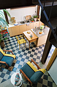 View down into open-plan kitchen with chairs on chequered floor