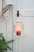 Lit candle in lantern hung from wooden door